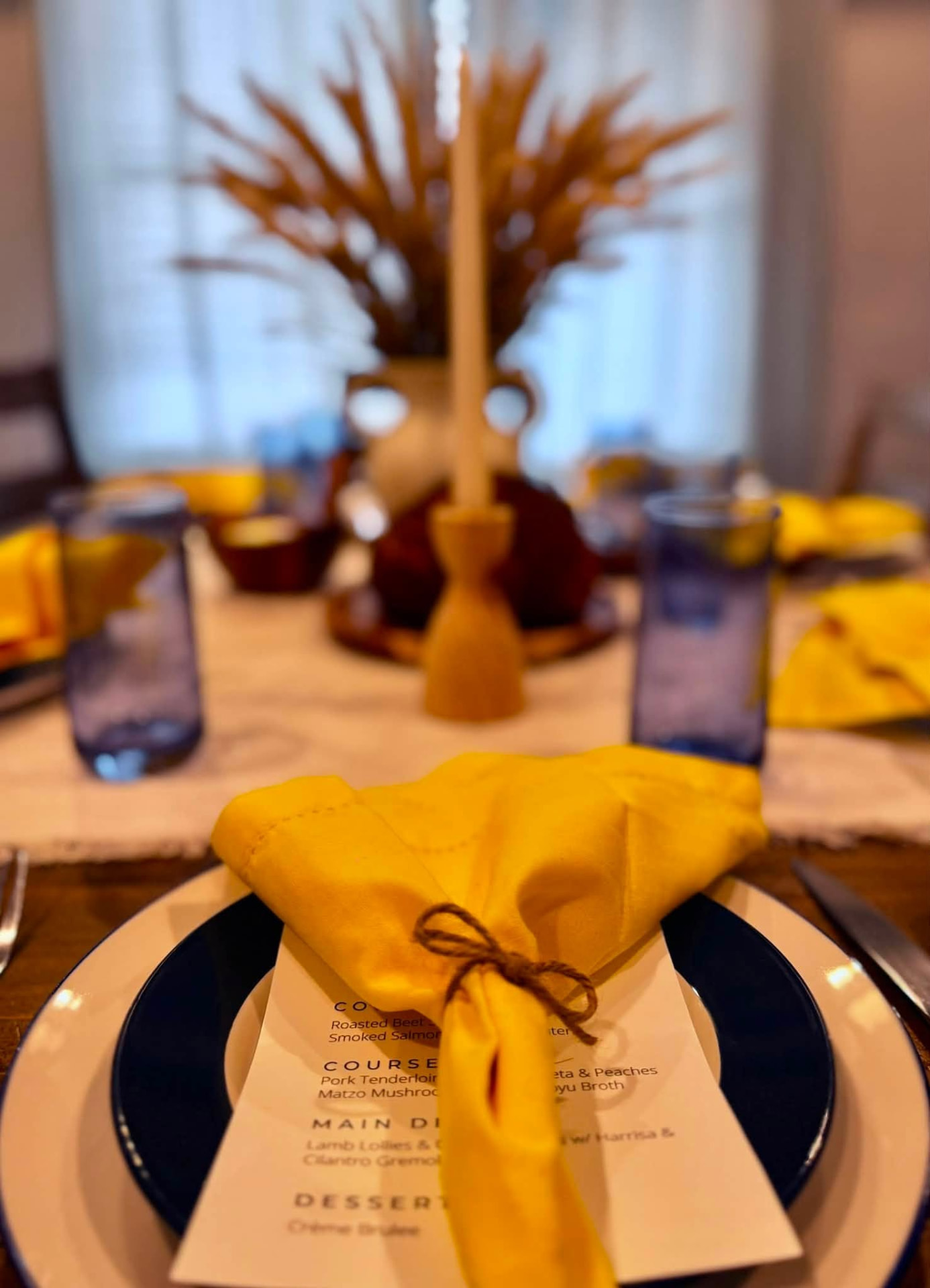Printed multi-course menu and place setting on a candlelit table at a luxury catered event in Virginia Beach, Virginia